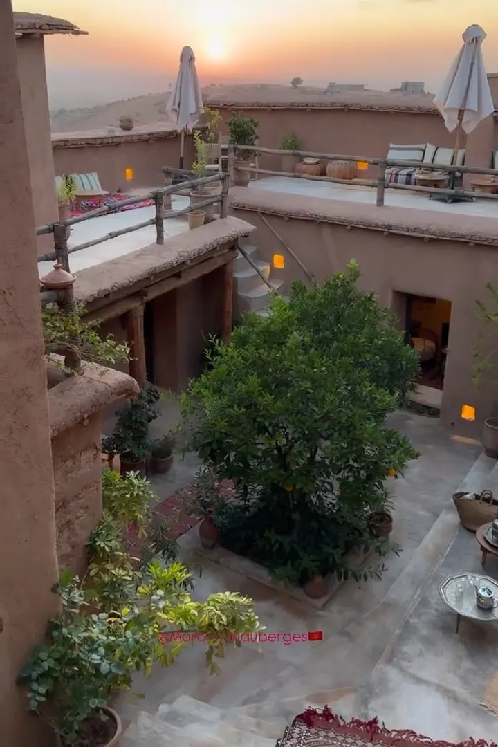 Earthen courtyard with a tree and terraces at sunset