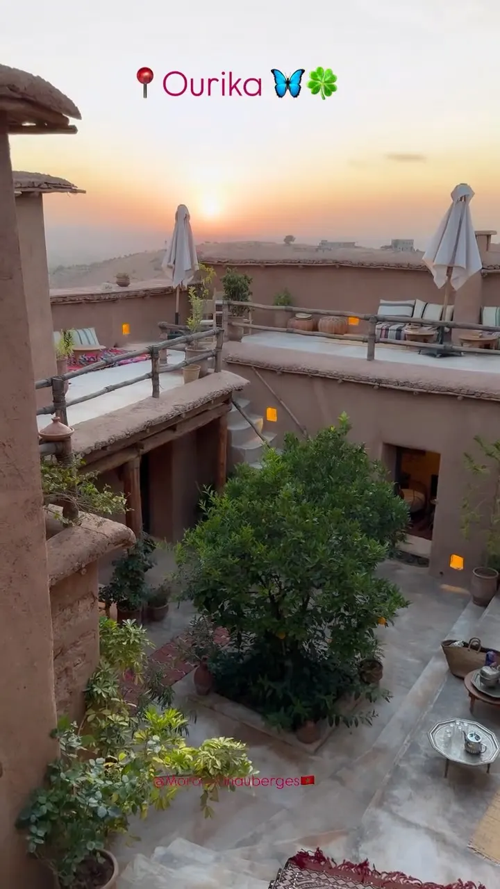 Cour intérieure en pisé avec un arbre et des terrasses au coucher du soleil