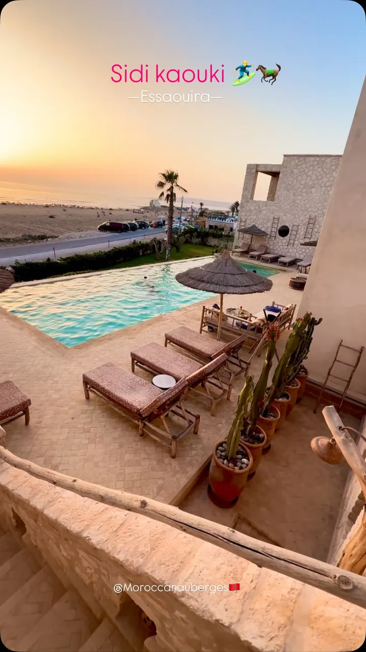 Terrasse en pierre surplombant la piscine et la plage au coucher du soleil
