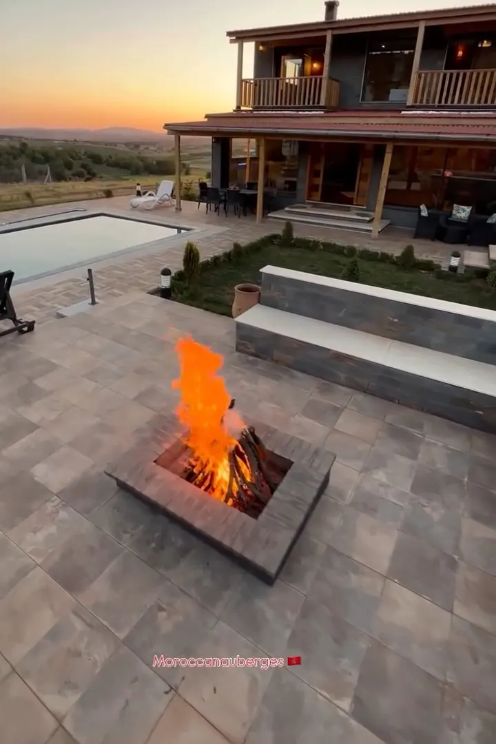 Wooden chalet with a pool and a fire pit at dusk