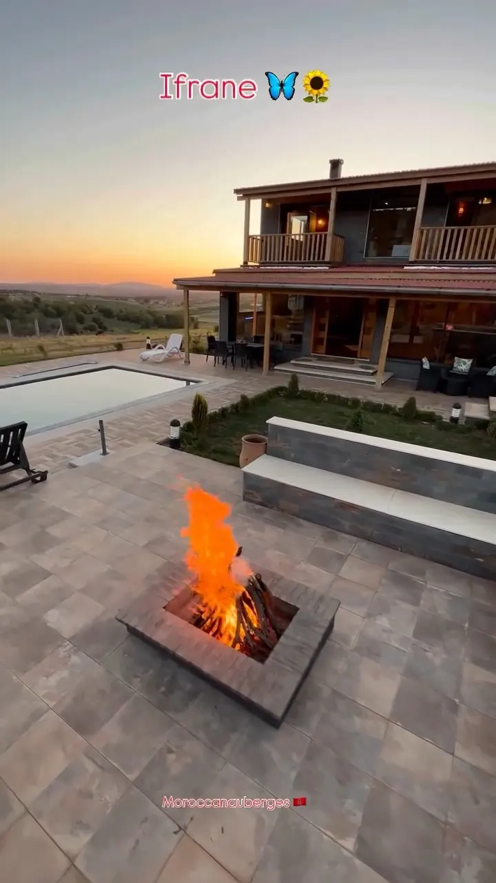 Chalet en bois avec piscine et feu de bois au coucher du soleil