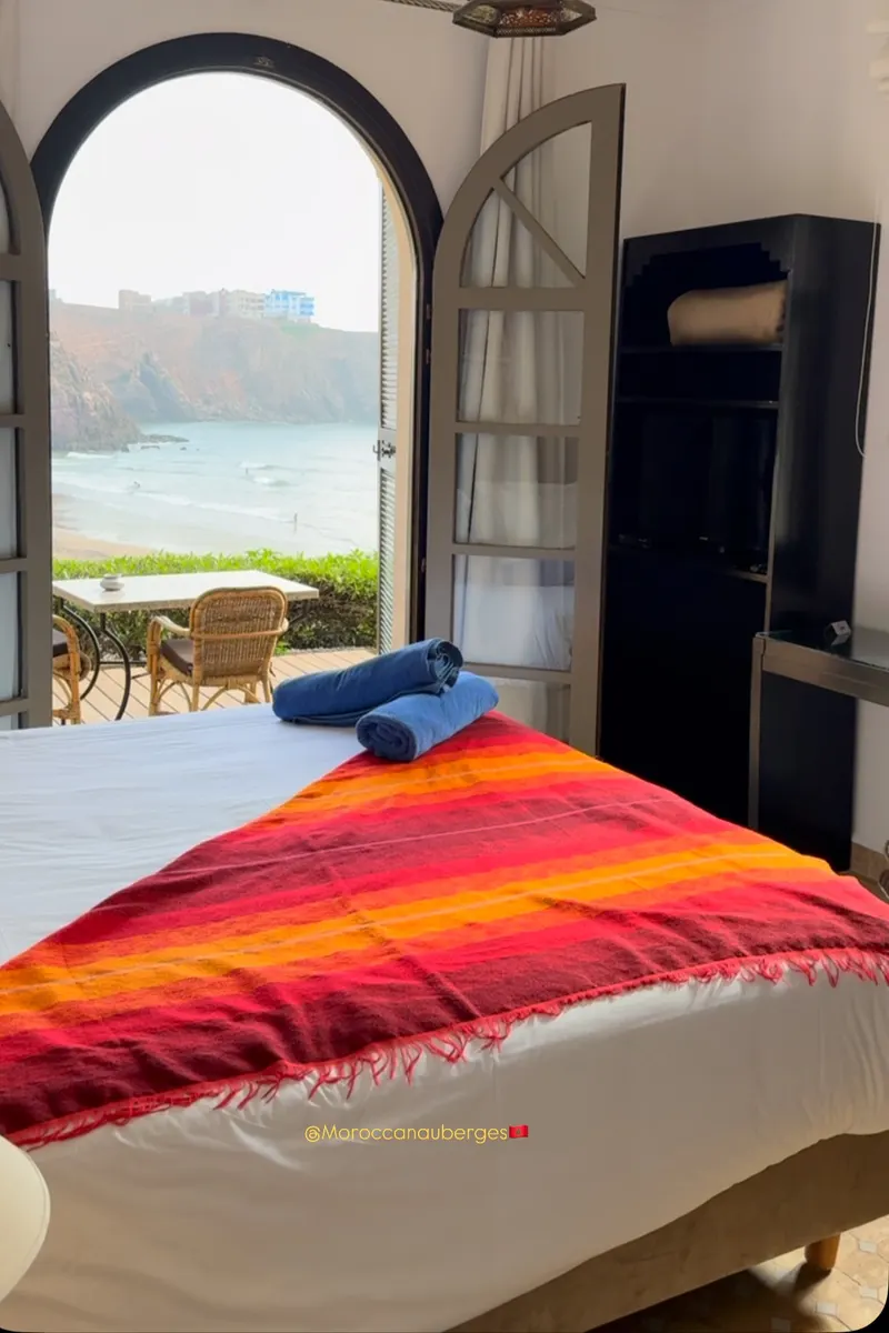 Chambre voûtée avec lit et vue sur une plage bordée de falaises